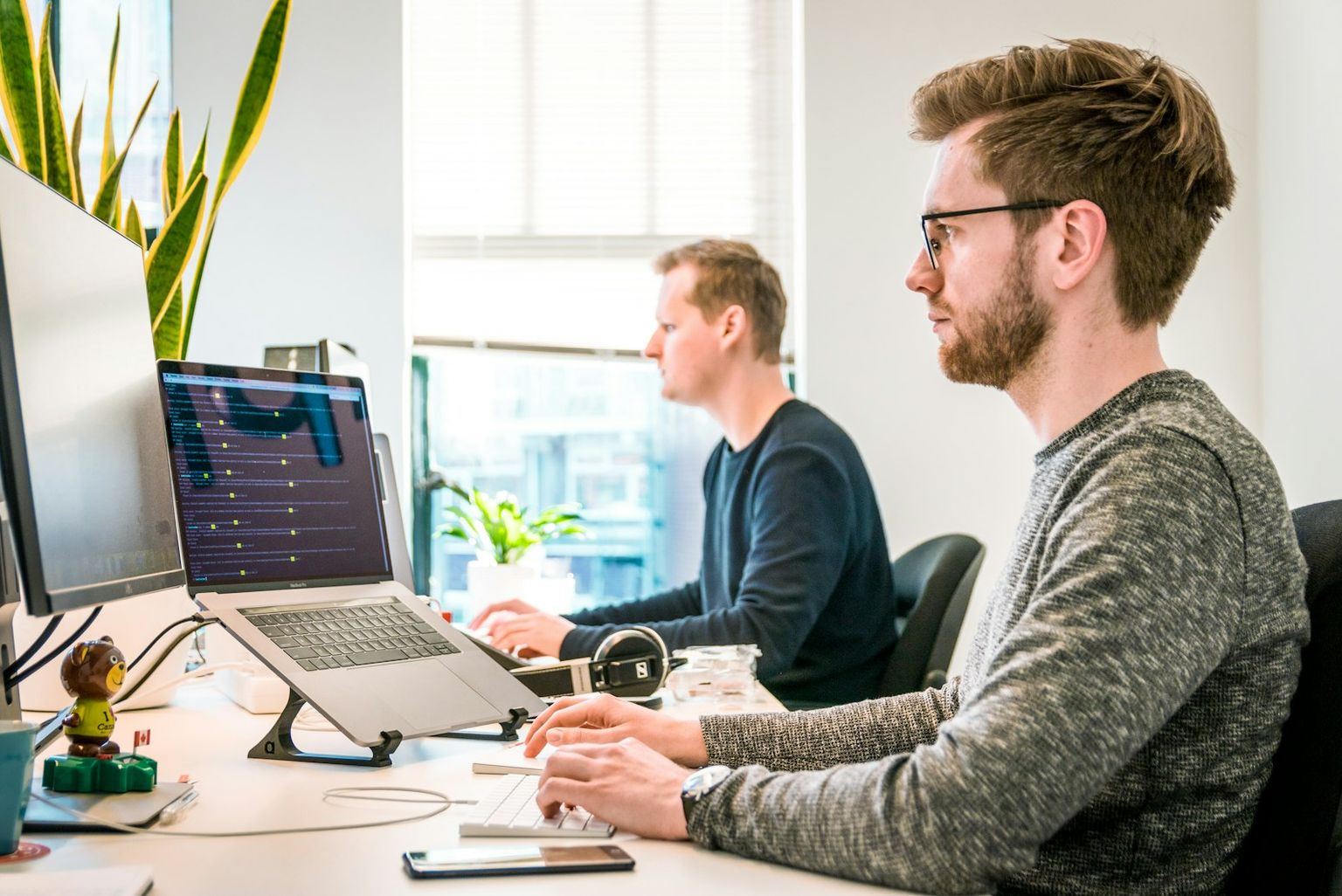 Zwei Entwickler arbeiten nebeneinander an ihren Bildschirmen